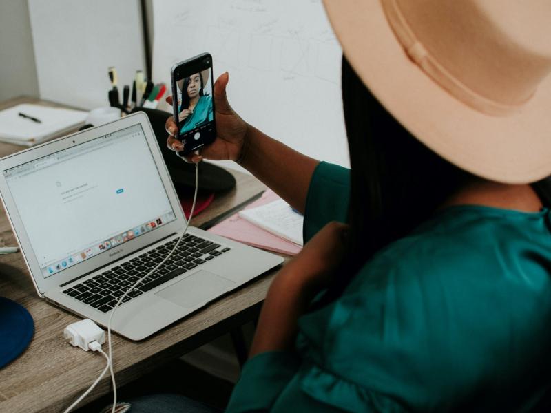 Une femme à son bureau, se filme en train de parler 
