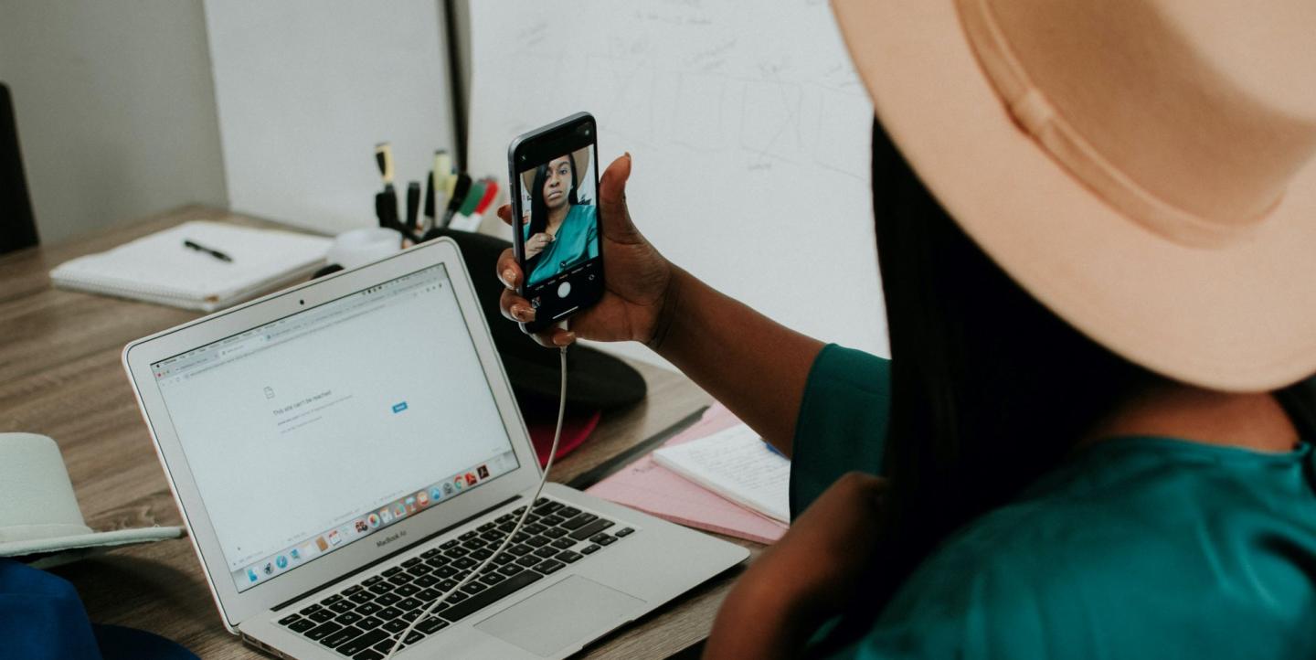 Une femme à son bureau, se filme en train de parler 