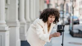 A woman setting up her phone on a tripod to record a video.