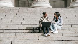 Two students sitting on outside steps. 