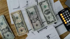 Stacks of money, a calculator on an Iphone and charts 