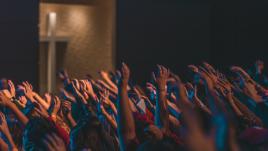 Personnes à l'église, les mains en l'air et un crucifix en fond