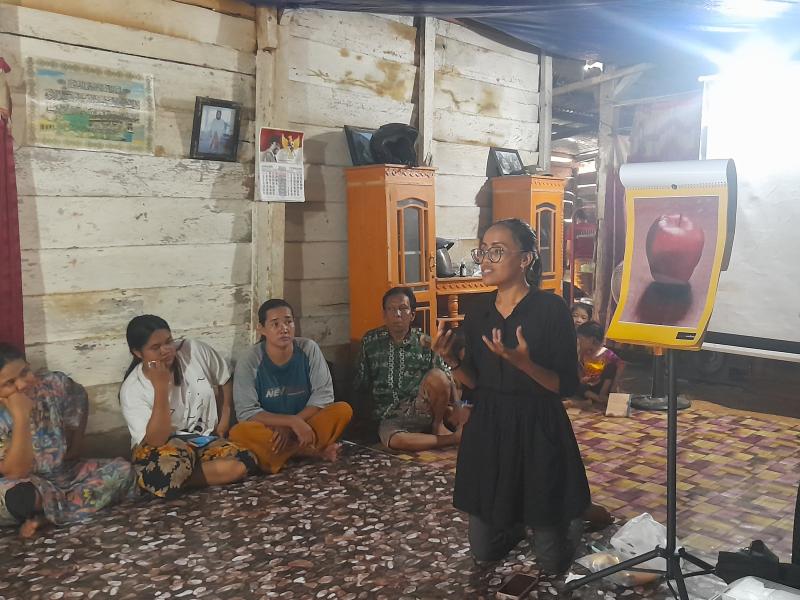 Zulfa in front of an image of an apple speaking to a group of people sitting on the floor